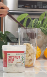 BareOrganics Coconut milk powder container with a blender and ingredients in the background
